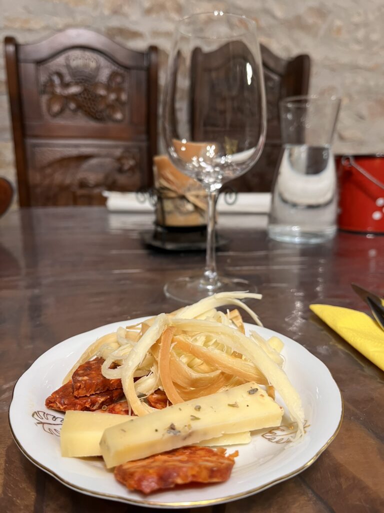 Wine glass, which a plate of cheese, sausage.