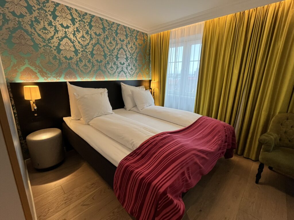 Hotel room with yellow curtains, bed and wallpaper