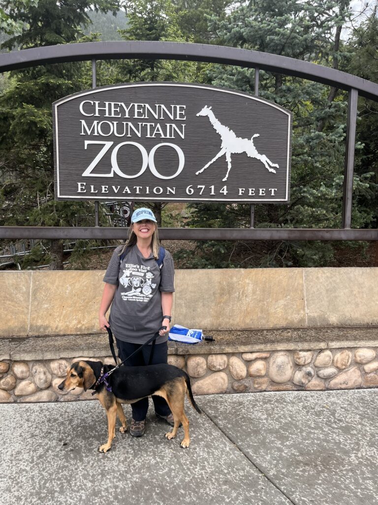woman and dog in front of zoo sign